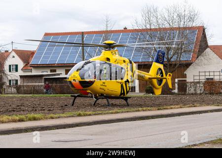 Stettenhofen, Baviera, Germania - 28 dicembre 2023: l'elicottero di salvataggio Christoph 40 dell'ADAC Luftrettung atterra in una zona residenziale durante una missione del medico di emergenza nel villaggio di Langweid OT Stettenhofen *** Rettungshubschrauber Christoph 40 der ADAC Luftrettung Landet bei einem Einsatz vom Notarzt im Dorf Langweid OT Stettenhofen in einer Wohnsiedlung Foto Stock