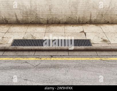 Una sezione di una strada vuota usurata e sporca, marciapiede pavimentato e muro di mattoni neri - rendering 3D. Foto Stock