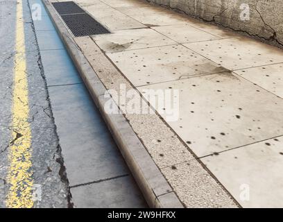 Una sezione di una strada vuota usurata e sporca, marciapiede pavimentato e muro di mattoni neri - rendering 3D. Foto Stock