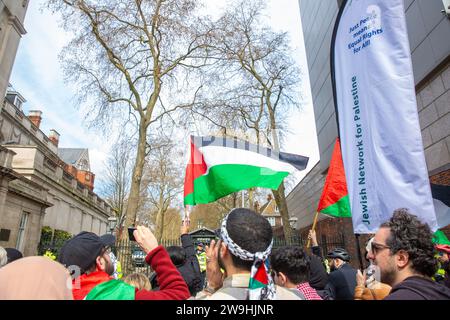 I manifestanti pro-palestinesi si riuniscono con le bandiere durante una protesta fuori dalle porte dell'ambasciata di Israele a Londra. Foto Stock