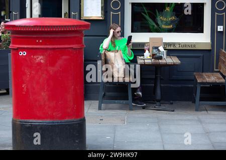 Il venerdì Santo, davanti a un pub nel centro di Londra, un acquirente riposa fuori. Foto Stock