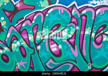 Street art urbana. Vivide lettere graffiti di colore verde e magenta, dipinte su una parete sotto il cavalcavia Fleetsbridge a Poole. Dorset, Inghilterra, Regno Unito. Foto Stock