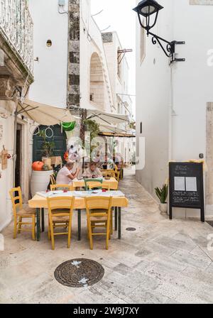 Locorotondo, Puglia, Italia - 5 ottobre 2023: I turisti si godono i ristoranti all'aperto nell'antico borgo di Locorotondo, in provincia di Bari. Foto Stock