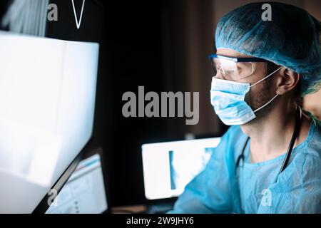 Il chirurgo esamina le immagini fluorografiche su un monitor in una sala operatoria di uno studio medico Foto Stock