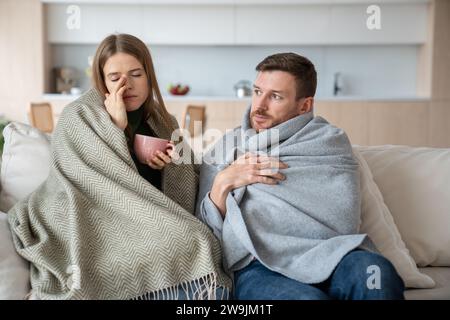 Coppia seduta a casa avvolta in plaid, si sente male, malato. Virus epidemici stagionali, influenza Foto Stock