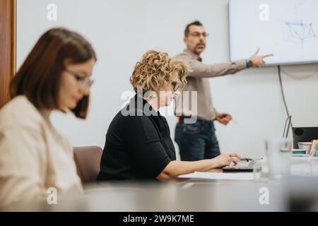 Professionisti aziendali di più generazioni in una sala riunioni, discutendo di statistiche e brainstorming per la crescita aziendale. Foto Stock