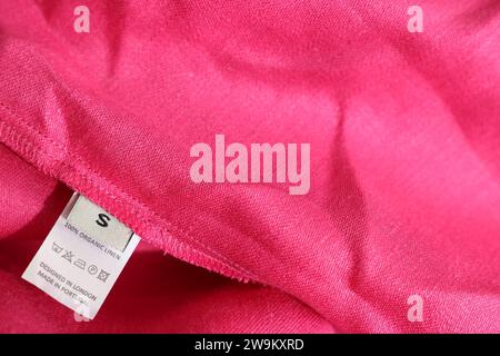 Etichetta di abbigliamento in diverse lingue su indumenti rosa, primo piano Foto Stock