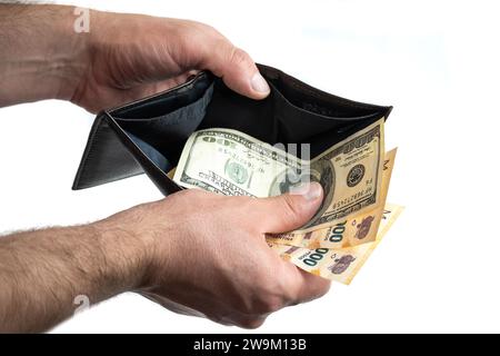 Mano con portafoglio che mostra banconote in dollari e banconote in peso argentino Foto Stock