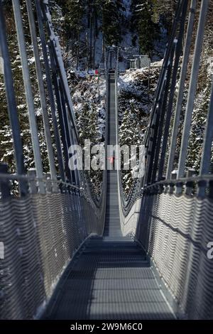 Una sola persona che attraversa il ponte sospeso Highline179 in una foto di un giorno d'inverno con un teleobiettivo Foto Stock