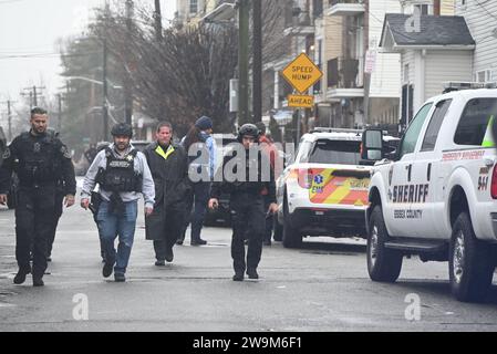 Newark, Stati Uniti. 28 dicembre 2023. Gli ufficiali SWAT si precipitano fuori dalla residenza con una persona che li trasporta in un'ambulanza dopo il lancio di un flash bang. Ufficio dello sceriffo della contea di Essex e squadre SWAT sulla scena di una residenza in Camden Street a Newark, New Jersey. Le autorità stavano tentando di eseguire un mandato di perquisizione giovedì mattina, quando il sospetto si e' barricato all'interno della residenza. Un flash-bang è stato sentito e gli ufficiali SWAT si sono trasferiti all'interno, una persona è stata poi portata in un'ambulanza in attesa dopo che la SWAT è entrata nella residenza. Credito: SOPA Images Limited/Alamy Live News Foto Stock