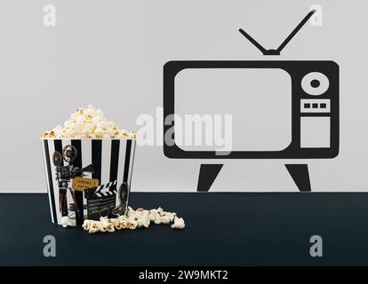 Layout creativo realizzato con secchiello per popcorn pieno di popcorn su sfondo bianco e nero con spazio per la copia a forma di tv. Concetto di film minimalista. Foto Stock