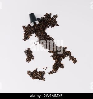 Composizione creativa con mappa dell'Italia fatta di chicchi di caffè tostati e tazza di caffè su sfondo bianco. Aspetto estetico realistico. Stile contemporaneo. Foto Stock