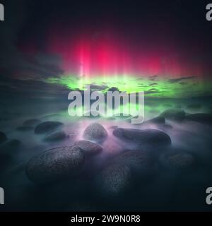 L'aurora boreale rosa e verde sopra la costa rocciosa, Donegal, Irlanda Foto Stock