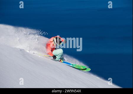 Una sciatrice (Hazel Birnbaum) scierà in neve profonda in una splendida giornata all'Heavenly Mountain Resort con il lago Tahoe sullo sfondo vicino al South Lake Tahoe, California. Foto Stock