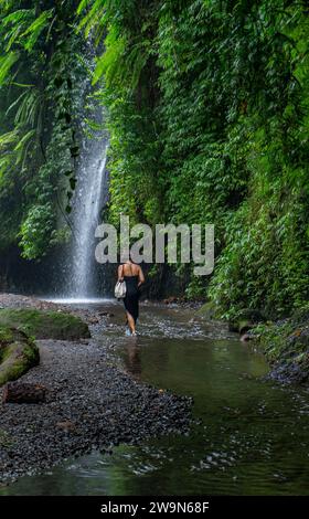 Donna che esplora la cascata Tukad Cepung a Bali Foto Stock