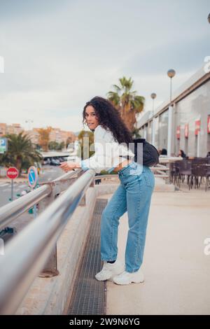 Donna sudamericana con i capelli ricci che sorride e guarda la fotocamera Foto Stock