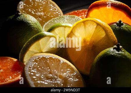 miscela di limone e mandarini a fette su sfondo nero Foto Stock