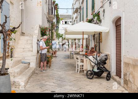 Locorotondo, Puglia, Italia - 5 ottobre 2023: I turisti si godono i ristoranti all'aperto nell'antico borgo di Locorotondo, in provincia di Bari. Foto Stock