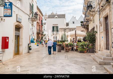 Locorotondo, Puglia, Italia - 5 ottobre 2023: I turisti si godono i ristoranti all'aperto nell'antico borgo di Locorotondo, in provincia di Bari. Foto Stock