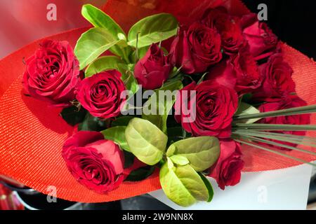 Una dozzina di bouquet di rose rosse avvolte in carta rossa, visto dall'alto. Ideale per San Valentino, festa della mamma o un regalo di compleanno o di appuntamenti. Foto Stock