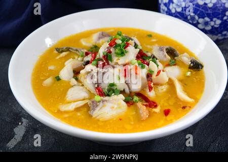 Le bacchette di primo piano raccolgono un pezzo di carne di pesce dal pesce Sichuan (Suan cai yu), il pesce piccante bollito con cavolo sottaceto in stile Sichuan, famoso mento Foto Stock