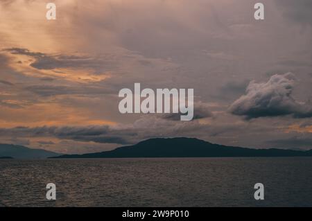 Siamo appena stati testimoni di un tramonto mozzafiato sulle calme acque del lago. Le nuvole riflettevano i colori vivaci del cielo, creando un capolavoro. Foto Stock