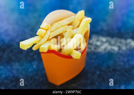 Patatine fritte dorate e croccanti servite in una classica tazza di carta, ideale per gli appassionati di fast food. viziatevi con una delizia deliziosa. Foto Stock