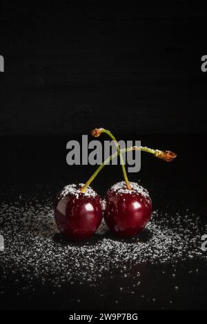 Zucchero versato su ciliegia rossa fresca su sfondo scuro con spazio per la copia - scuro e lungoso Foto Stock