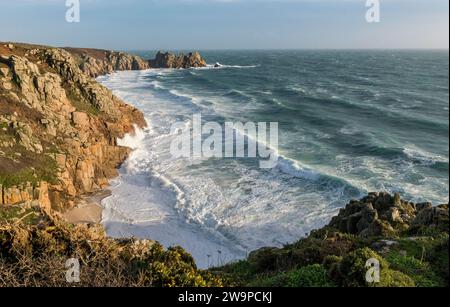 Mari mossi che si infrangono sulla spiaggia di Pedn Vounder, in Cornovaglia, mentre Storm Gerrit passa nel Natale del 2023. Il Logan Rock è sullo sfondo Foto Stock