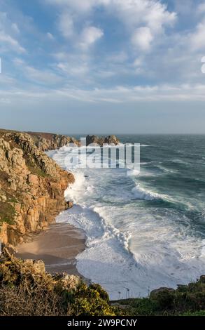 Mari mossi che si infrangono sulla spiaggia di Pedn Vounder, in Cornovaglia, mentre Storm Gerrit passa nel Natale del 2023. Il Logan Rock è sullo sfondo Foto Stock