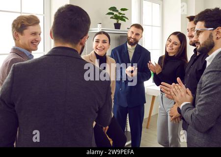 Uomini d'affari che applaudono il loro collega di successo durante una riunione o una conferenza Foto Stock