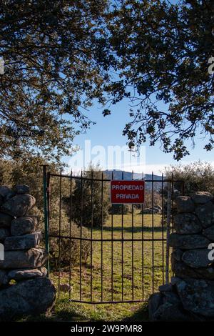 Traduzione: Proprietà privata. Cancello della barra di ferro su una recinzione in pietra a secco che dà accesso a un pascolo privato Foto Stock