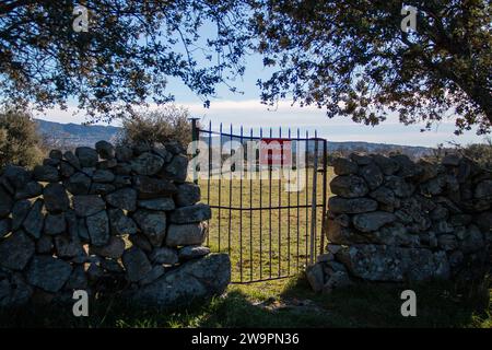 Traduzione: Proprietà privata. Cancello della barra di ferro su una recinzione in pietra a secco che dà accesso a un pascolo privato Foto Stock