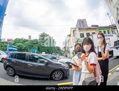 23 - 2023 febbraio - Kuala Lumpur Malesia - giovani asiatici in maschera visitano la capitale malese e scattano foto con i loro telefoni. Immagine con fisheye l Foto Stock