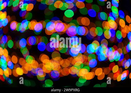 Grandi palline bokeh verdi, rosse, arancioni e blu che girano e creano un ornamento magico. Sfondo astratto ad alta risoluzione. Foto vera. Foto Stock
