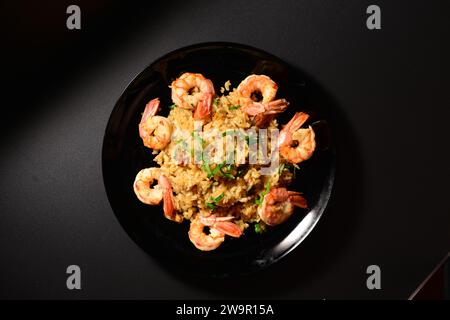 Risotto con cozze e gamberi su un piatto nero. Foto Stock