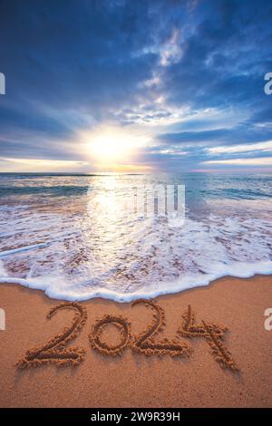 Felice anno nuovo 2024 testo concettuale sulla spiaggia di sabbia all'alba paesaggio naturale verticale Foto Stock