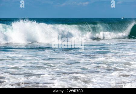 Big Waves si schianta creando schiuma bianca che vaporizza nell'aria. Spiaggia di Sopelana vicino a Bilbao. Surfisti in attesa dell'onda perfetta. Giornata di relax Foto Stock