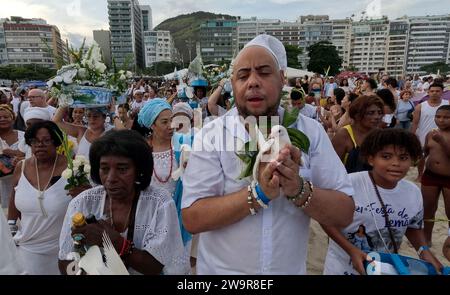 Rio de Janeiro, Rio de Janeiro, Brasile. 29 dicembre 2023. Ricoperti di bianco e con mazzi di gigli, i praticanti della fede afro-brasiliana dell'Umbanda si sono riuniti per onorare la dea del mare lemanja in un tradizionale tributo di Capodanno sulla spiaggia di Copacabana a Rio de Janeiro. Alla fine di ogni anno i fedeli presentano regali alla Dea del Mare, per ringraziare e chiedere benedizioni per il prossimo anno. (Immagine di credito: © Bob Karp/ZUMA Press Wire) SOLO USO EDITORIALE! Non per USO commerciale! Crediti: ZUMA Press, Inc./Alamy Live News Foto Stock