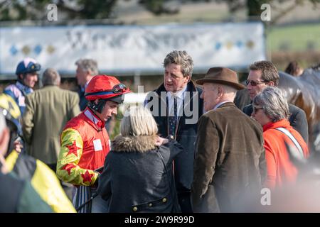 Jockey Rex Dingle e l'allenatore Jeremy Scott si incontrano con i proprietari nel terreno di parata di Wincanton prima di correre a Ballyblack Foto Stock