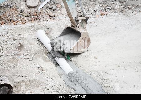 I tubi vengono innaffiati con dumper per cemento e escavatori Foto Stock