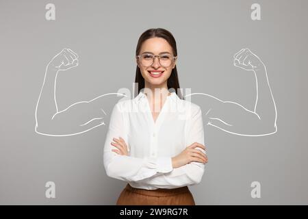 Donna sicura di sé su sfondo grigio. Illustrazione delle braccia muscolari dietro di lei Foto Stock