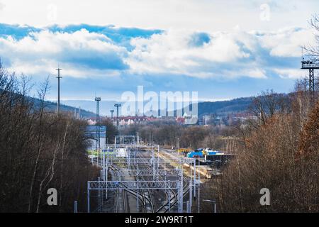 Stazione ferroviaria tra alberi con una città e una montagna sullo sfondo Foto Stock