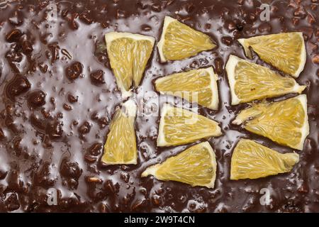 Vista dall'alto dei segmenti arancioni disposti in forma triangolare sulla consistenza di cioccolato e mandorle di una torta al cacao. Consistenza e sapori. Foto Stock