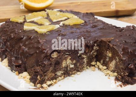 Primo piano che cattura l'interno ricco di nocciole di una torta al cioccolato decadente con mandorle, nocciole e un tocco vivace di arancia fresca. Foto Stock