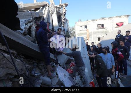 I residenti e le squadre di difesa civile conducono operazioni di ricerca e salvataggio sotto le macerie a seguito di un attacco israeliano i residenti e le squadre di difesa civile conducono operazioni di ricerca e salvataggio sotto le macerie a seguito di un attacco israeliano all'edificio della famiglia al-Wawi nel campo di Nuseirat, Striscia di Gaza, il 30 dicembre 2023. Foto di Naaman Omar apaimages Nuseirat Striscia di Gaza territorio palestinese 301223 Nusairat NAA 0021 Copyright: XapaimagesxNaamanxOmarxxxapaimagesx Foto Stock