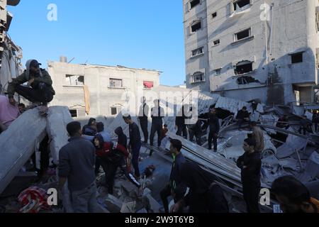 I residenti e le squadre di difesa civile conducono operazioni di ricerca e salvataggio sotto le macerie a seguito di un attacco israeliano i residenti e le squadre di difesa civile conducono operazioni di ricerca e salvataggio sotto le macerie a seguito di un attacco israeliano all'edificio della famiglia al-Wawi nel campo di Nuseirat, Striscia di Gaza, il 30 dicembre 2023. Foto di Naaman Omar apaimages Nuseirat Striscia di Gaza territorio palestinese 301223 Nusairat NAA 0019 Copyright: XapaimagesxNaamanxOmarxxxapaimagesx Foto Stock