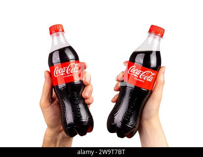 Berlino, Germania 16 dicembre 2023 Coca Cola in bottiglie di plastica in mani, applausi, isolato su bianco Foto Stock