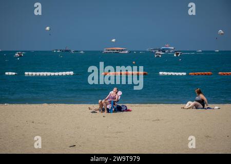 Pattaya, Thailandia. 27 dicembre 2023. Le donne occidentali si vedono prendere il sole sulla spiaggia di Pattaya. La spiaggia di Pattaya è una rinomata destinazione turistica in Thailandia. Ma mentre la città di Pattaya si è guadagnata una reputazione per la sua vivace vita notturna e le opzioni di intrattenimento, non è focalizzata esclusivamente sul servizio di ristorazione per viaggiatori singoli maschi. Oltre alla sua vita notturna, la città attrae diversi turisti, tra cui famiglie, coppie e individui di tutte le età, per lo shopping, le attività acquatiche e il relax sul mare. Credito: SOPA Images Limited/Alamy Live News Foto Stock