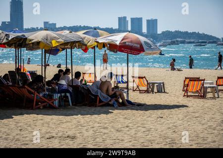 Pattaya, Thailandia. 27 dicembre 2023. I turisti sono visti sulle sdraio, sulla spiaggia di Pattaya. La spiaggia di Pattaya è una rinomata destinazione turistica in Thailandia. Ma mentre la città di Pattaya si è guadagnata una reputazione per la sua vivace vita notturna e le opzioni di intrattenimento, non è focalizzata esclusivamente sul servizio di ristorazione per viaggiatori singoli maschi. Oltre alla sua vita notturna, la città attrae diversi turisti, tra cui famiglie, coppie e individui di tutte le età, per lo shopping, le attività acquatiche e il relax sul mare. Credito: SOPA Images Limited/Alamy Live News Foto Stock